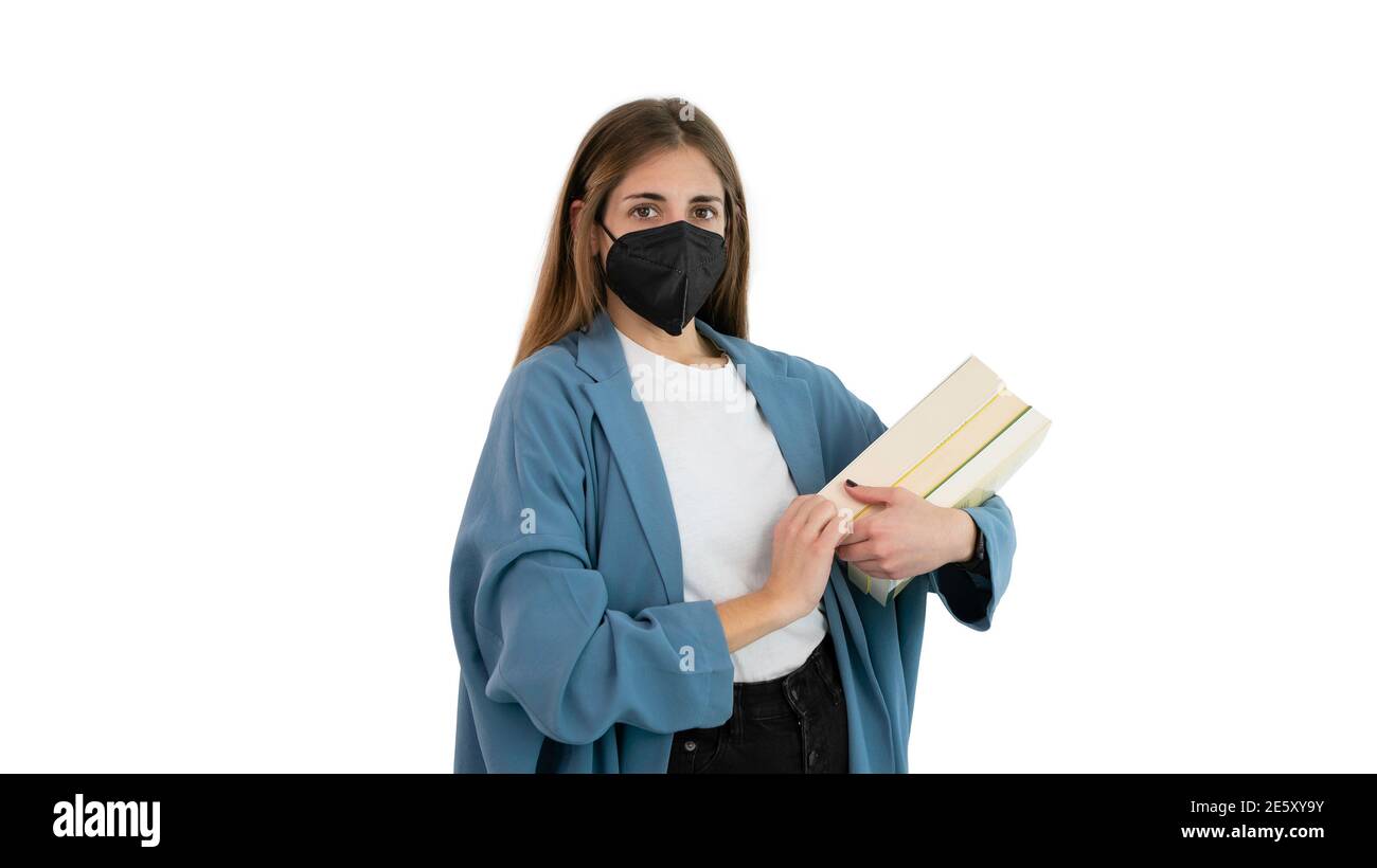 Portrait d'une étudiante ou d'une jeune fille d'université avec un masque noir et plusieurs livres sur son bras. Concept des études pendant le Covid 19 ou le coronavirus PAN Banque D'Images