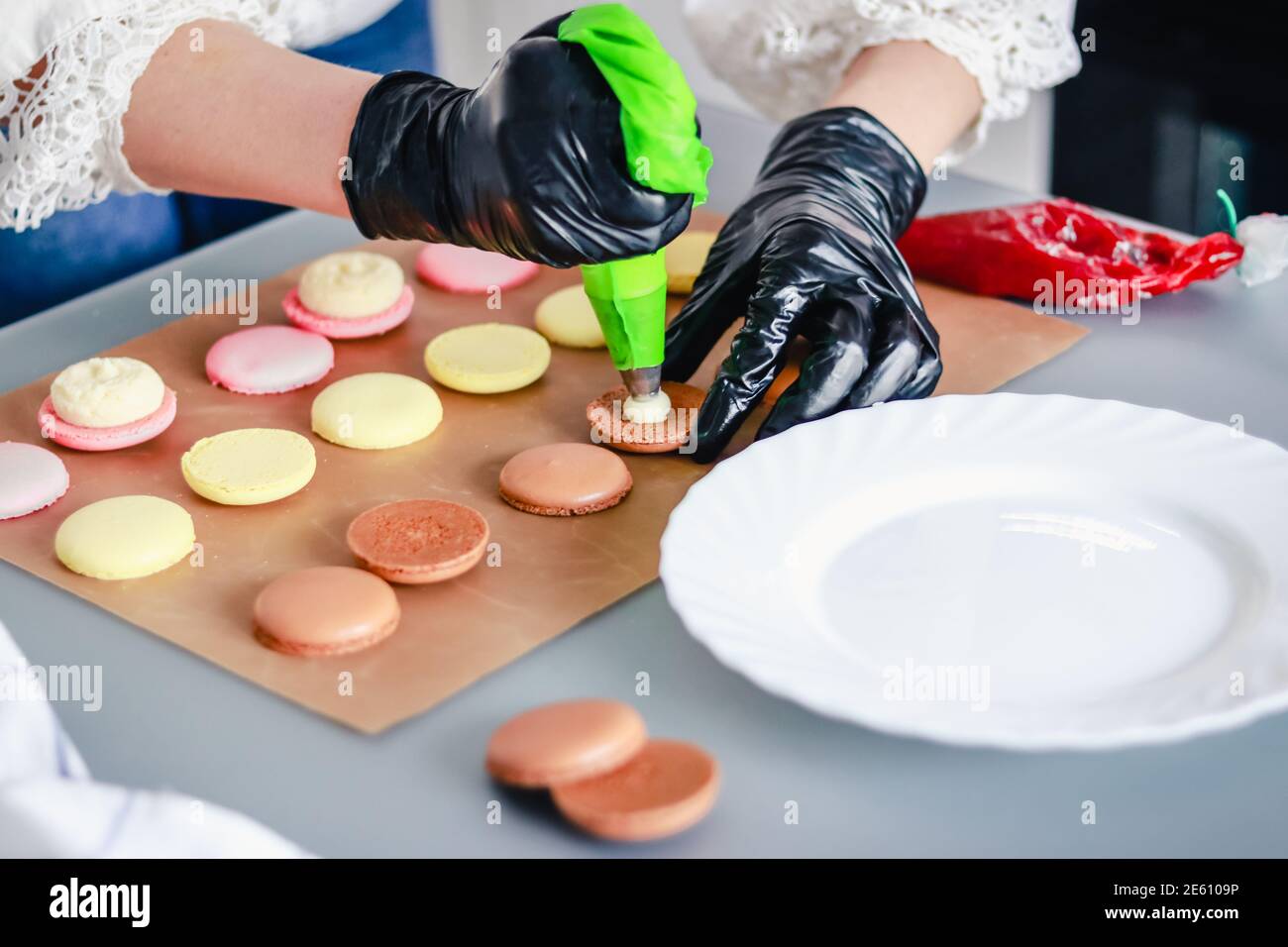 Le confiseur en gants de caoutchouc noir fait des gâteaux de macaron avec  de la confiture Photo Stock - Alamy