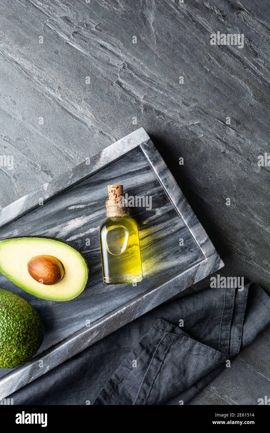 Huile d'avocat saine dans une bouteille de verre, décorée avec des tranches d'avocat sur fond de pierre avec espace de copie Banque D'Images