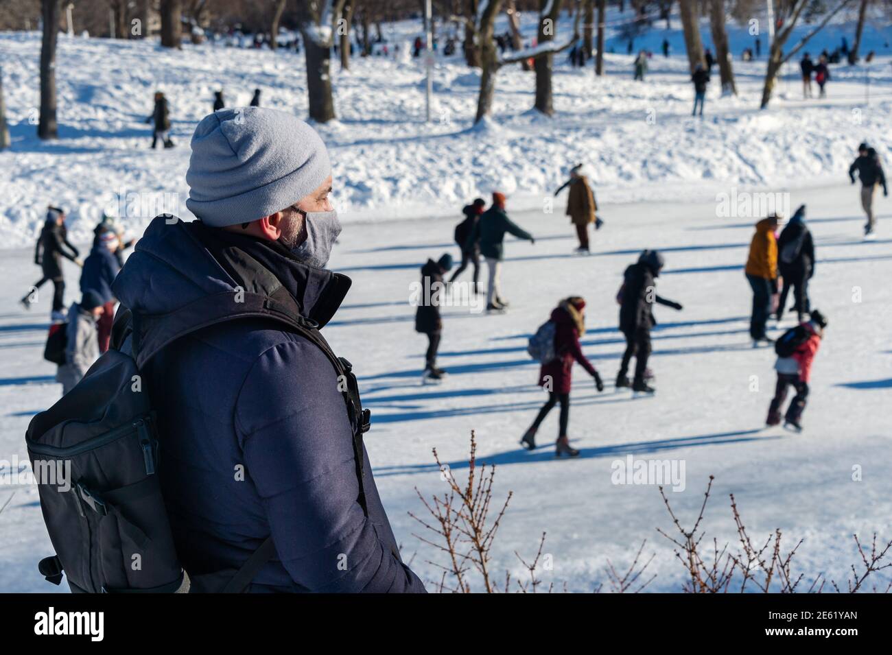 Homme portant un masque de protection pendant la pandémie Covid-19 regardant la glace patineurs Banque D'Images