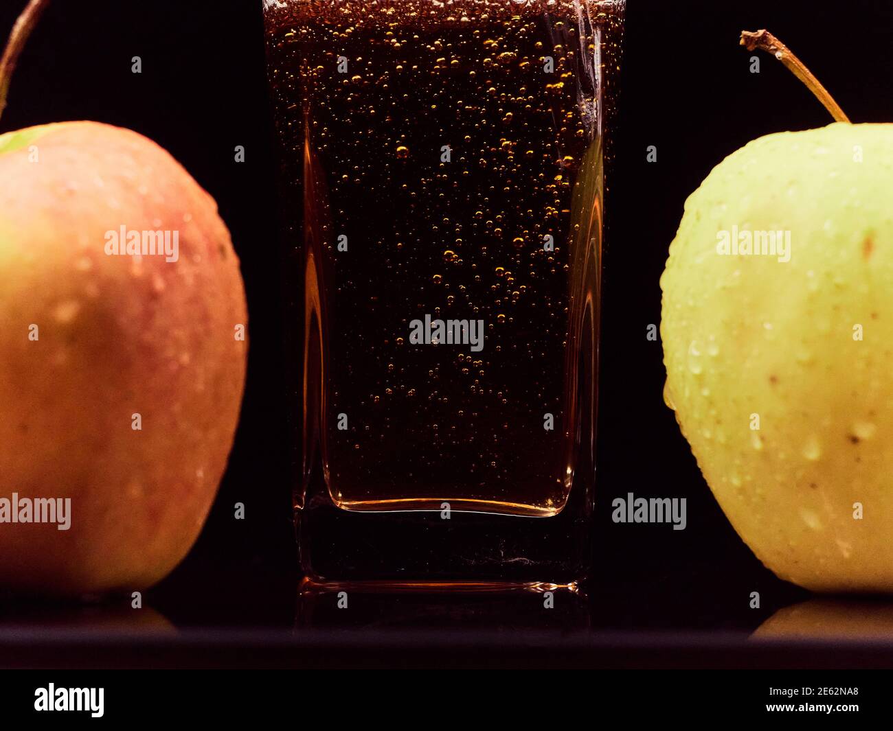 Gros plan sur le versement du jus de pomme frais dans le verre et les pommes vertes sur fond noir. Aliments sains, vitamines, fruits Banque D'Images