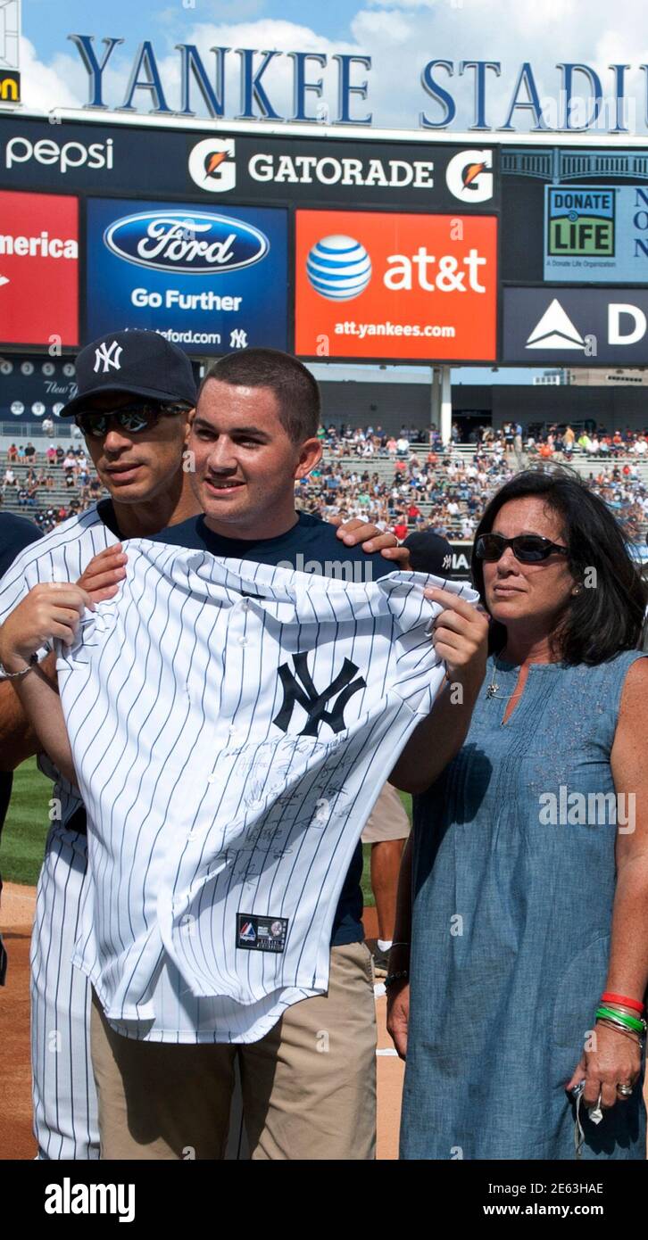 Heart transplant recipient Colby Salerno (C) poses with his mother Kelly  Salerno (R) and New York Yankees manager Joe Girardi (L) after receiving a  team jersey, before the Yankees play the Boston