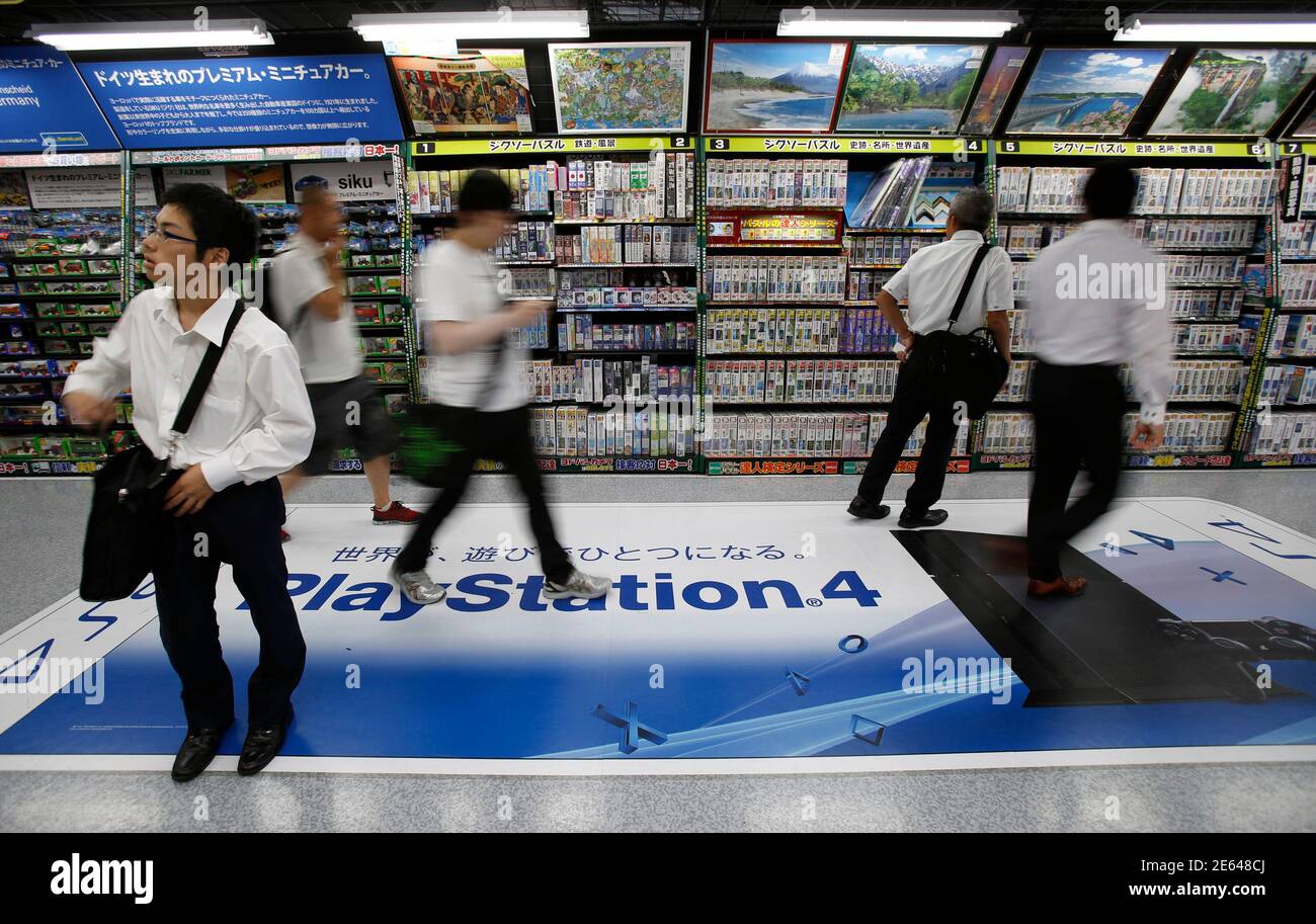 People walks on a floor advertising poster of Sony Corp's PlayStation 4  console at an electronics retail store in Tokyo July 16, 2014. Japan's Sony  Corp is hammering out plans to rise