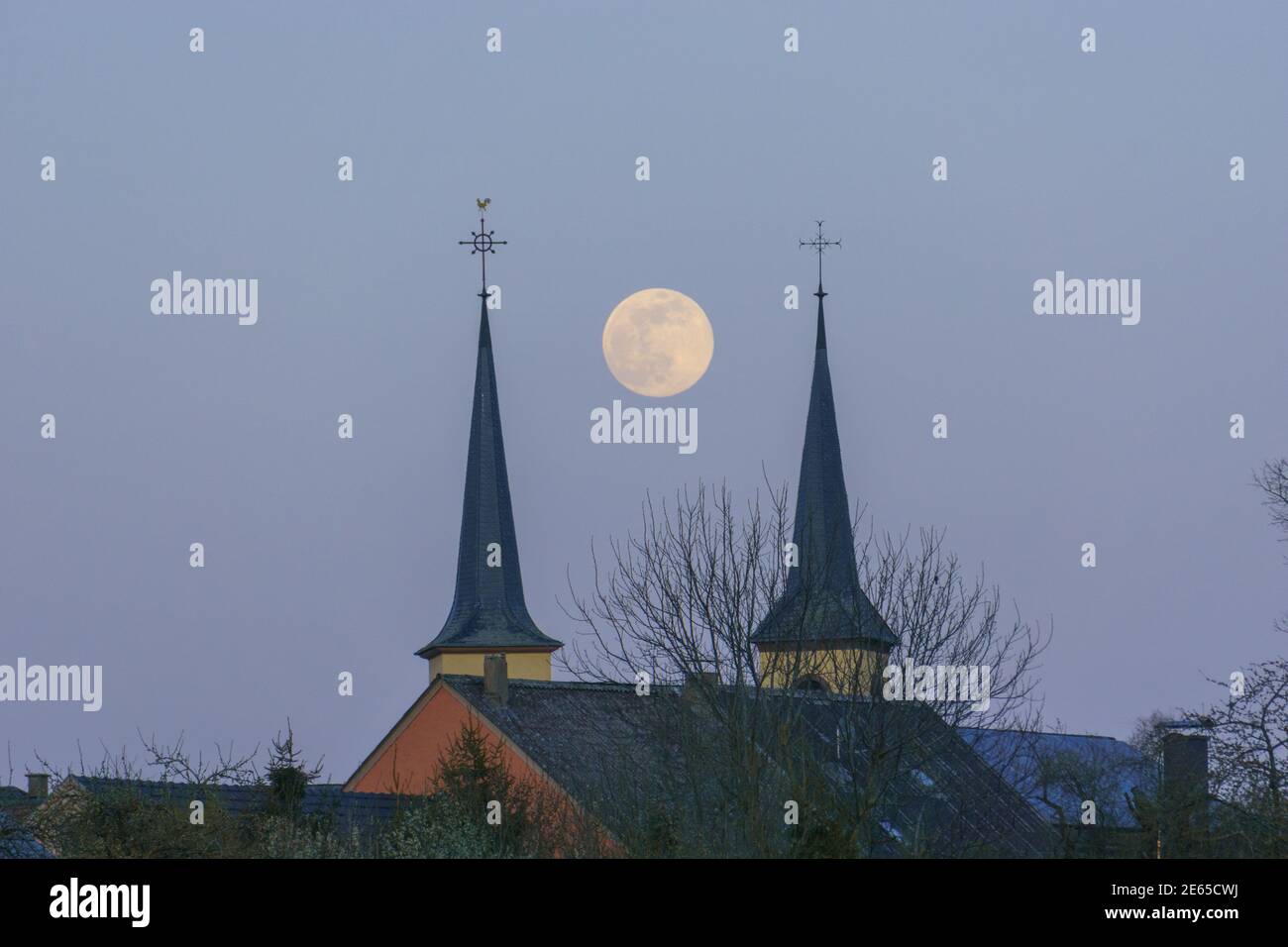 Pleine lune entre deux tours d'église dans le bleu ciel du soir Banque D'Images
