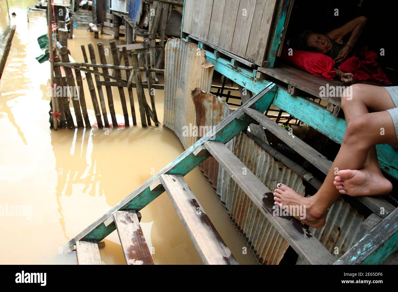 An elderly woman rests in her house as flood waters surround it in Kandal  province October 11, 2011. Monsoon rains, floods and landslides have killed  207 people in Cambodia since August 13