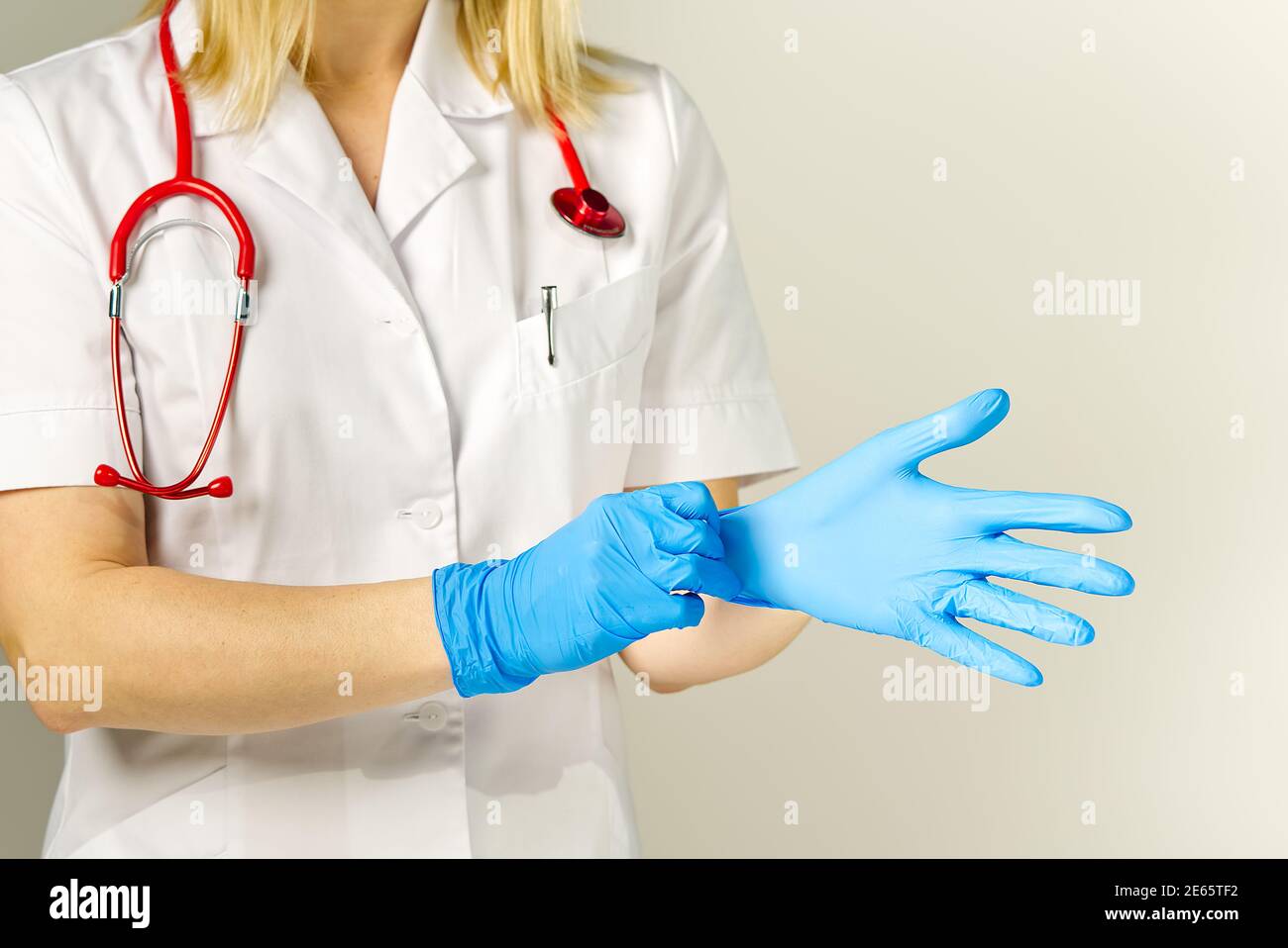 Gros plan lumineux du médecin avec stéthoscope rouge. Met sur des gants de protection, fond médical Banque D'Images