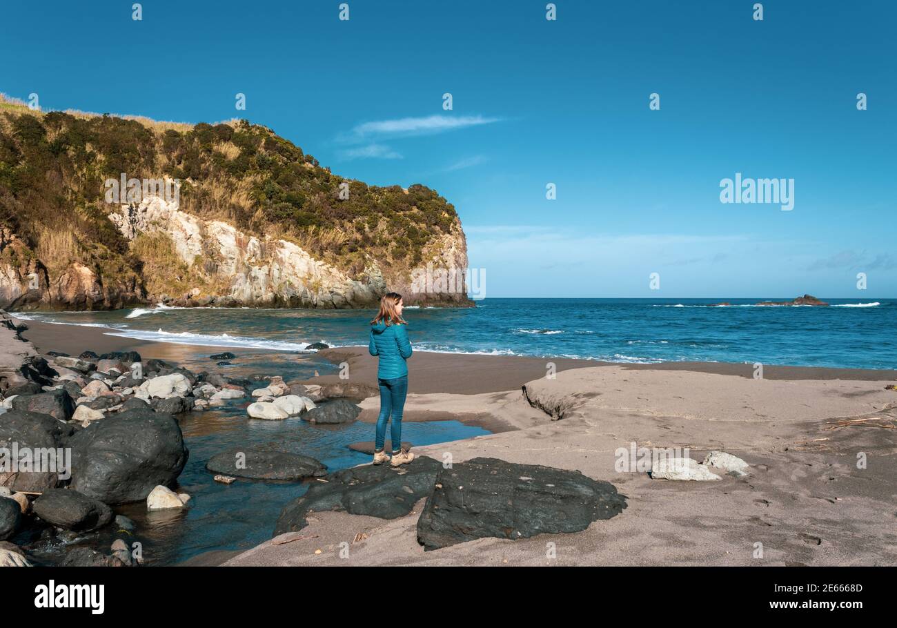 Une personne à la plage, femme, solo, sable noir, Açores, île de Sao Miguel, destination de voyage. Banque D'Images
