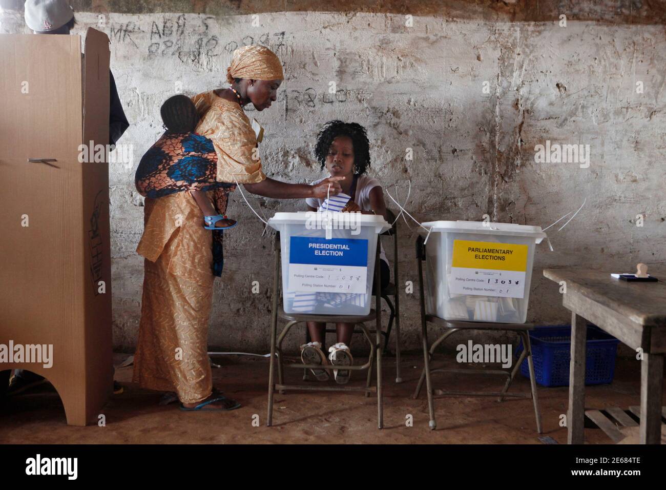 A woman carrying a baby on her back votes during presidential elections in  Freetown November 17, 2012. Sierra Leoneans vote on Saturday in elections  they hope can propel the small West African