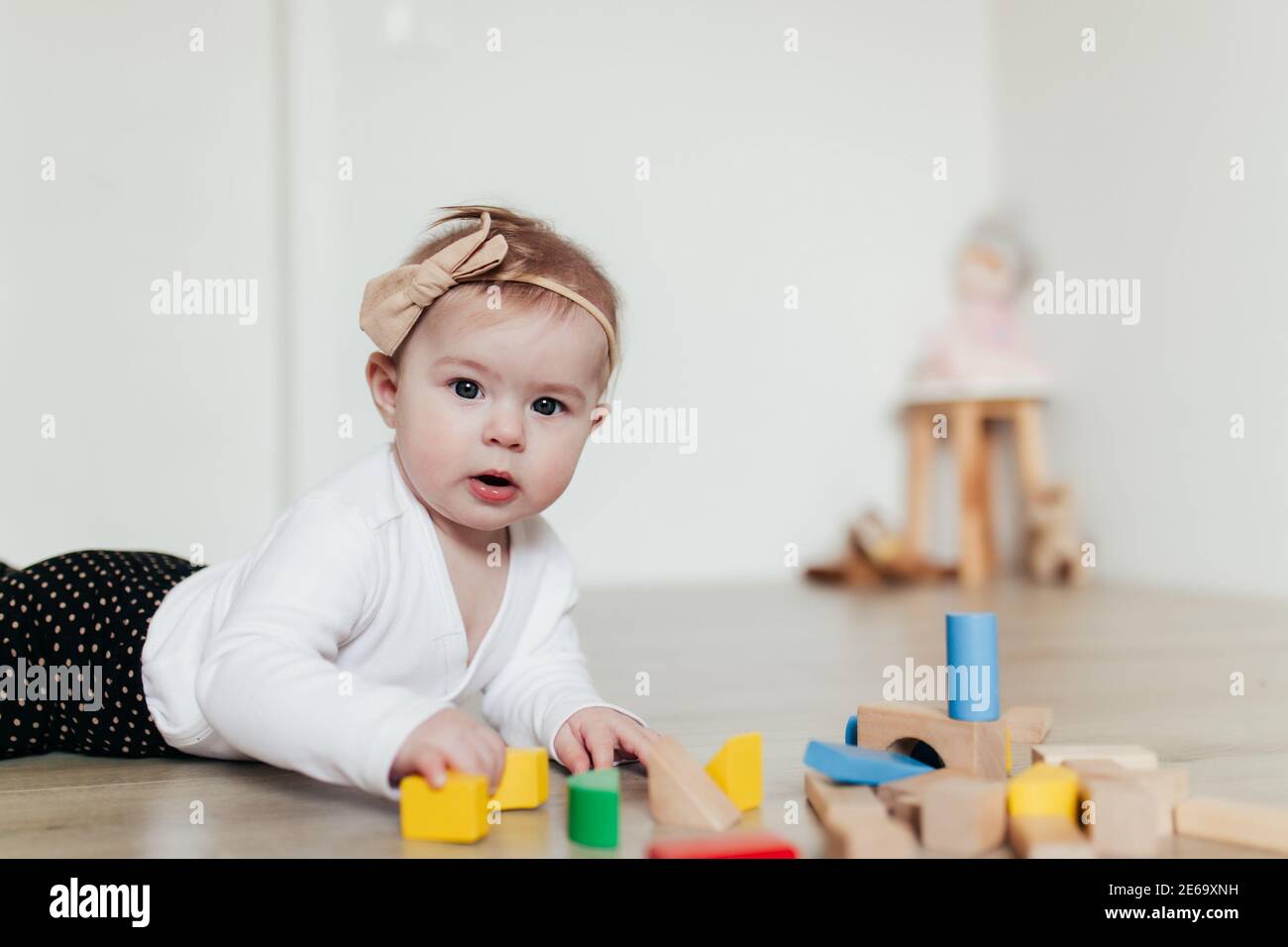 Petit enfant jouant avec des blocs de construction en bois colorés. Arrière-plan flou Banque D'Images