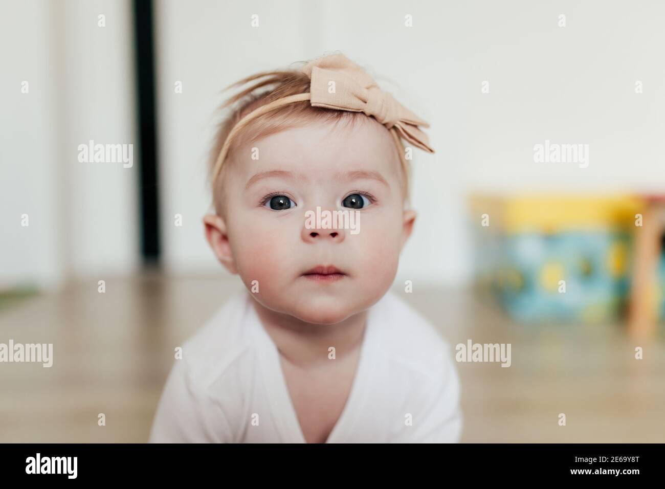 Petite fille de bébé avec arc regardant l'appareil photo. Arrière-plan flou Banque D'Images