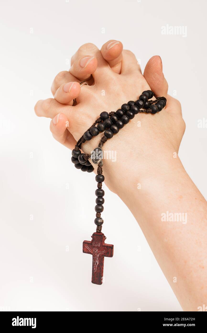 mains d'une femme tenant un rosaire et priant. Arrière-plan blanc. Banque D'Images
