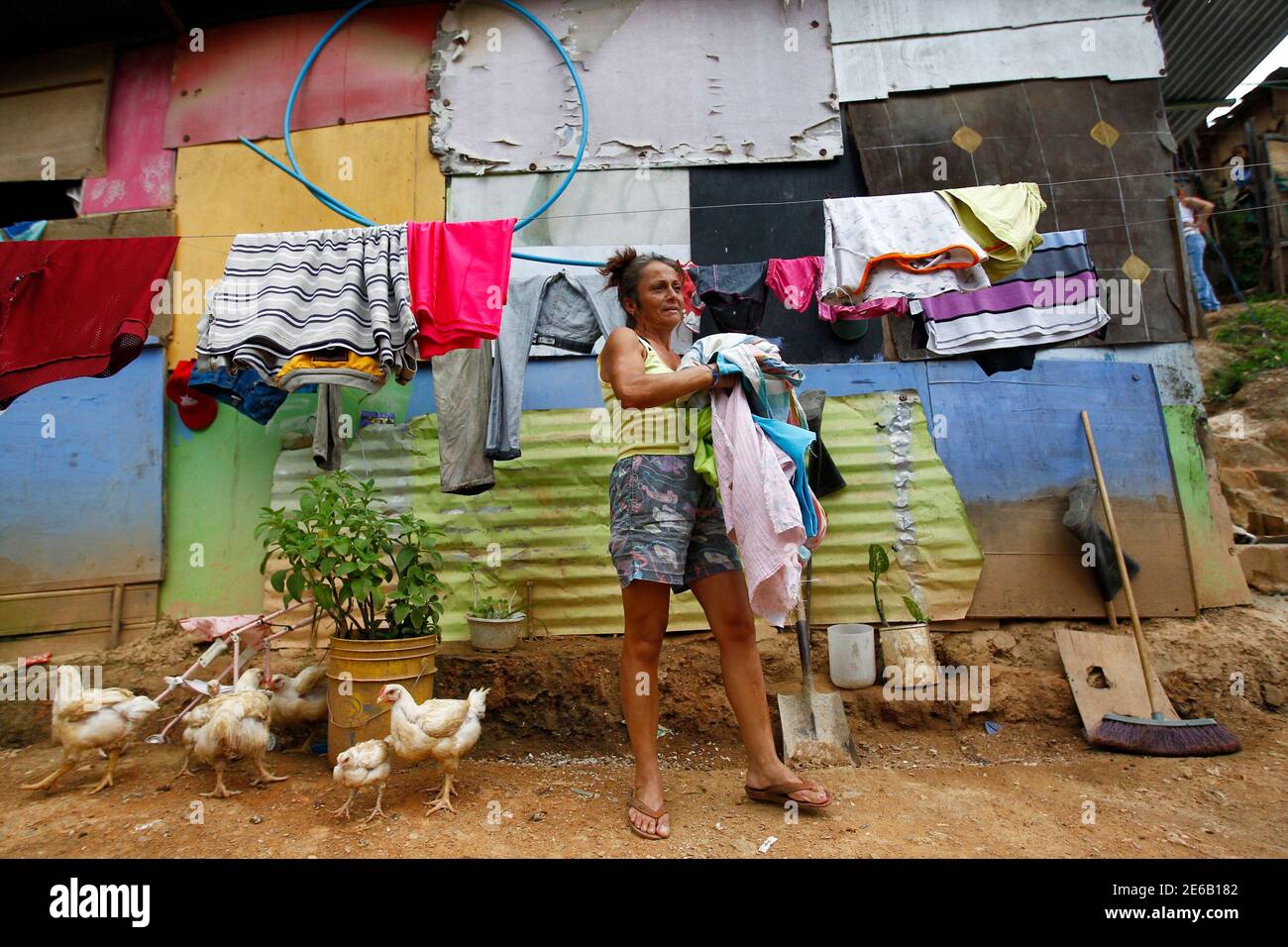 Maria Colmenares pick up her clothes outside her shack in Las Mayas slum in  Caracas May 31, 2011. Despite being in power for 12 years and bringing  plenty of new schools and