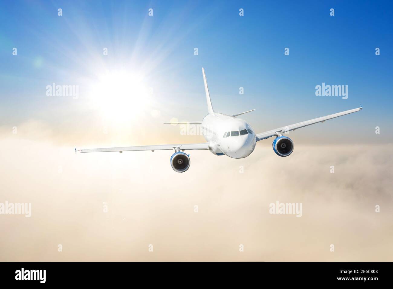 Avion civil survolant les nuages dans la lumière du coucher du soleil. Concept de voyage rapide, de vacances et d'affaires Banque D'Images