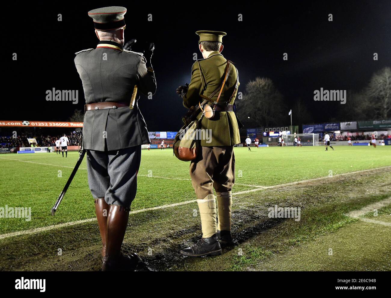 Two men wearing replica World War I British and German army uniforms watch  a soccer match between the British Army and German Bundeswehr at Aldershot  Town FC stadium in Aldershot in south