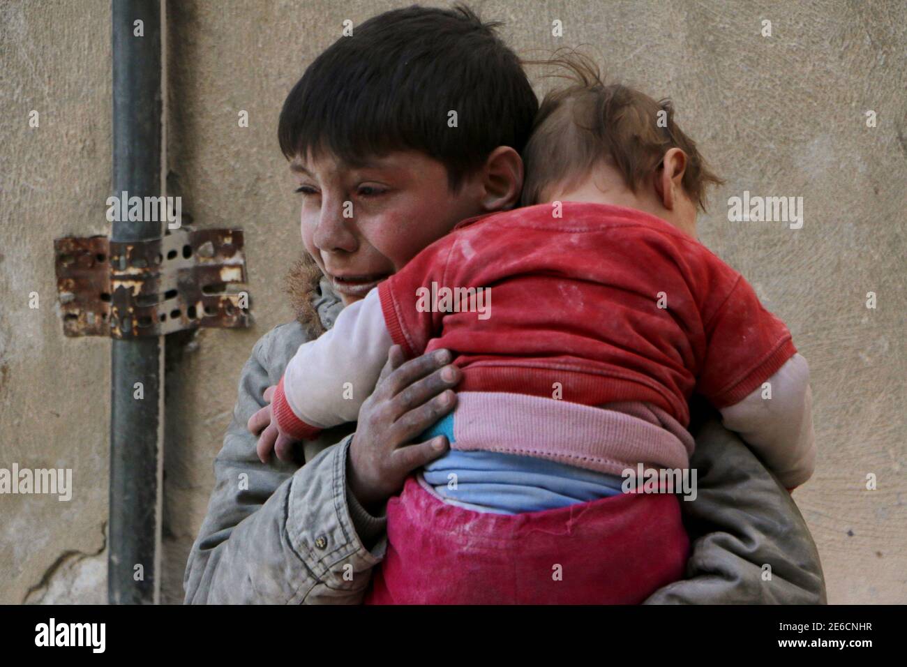 A boy holds his baby sister saved from under rubble, who survived what  activists say was an airstrike by forces loyal to Syrian President Bashar  al-Assad in Masaken Hanano in Aleppo February