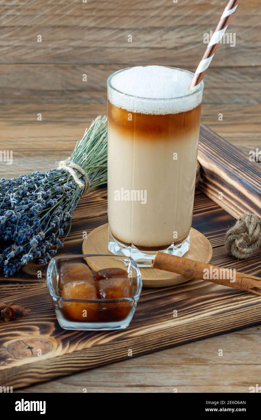 Latte ou Cappuccino avec mousse de lait et lavande dans un grand verre sur plateau en bois Banque D'Images