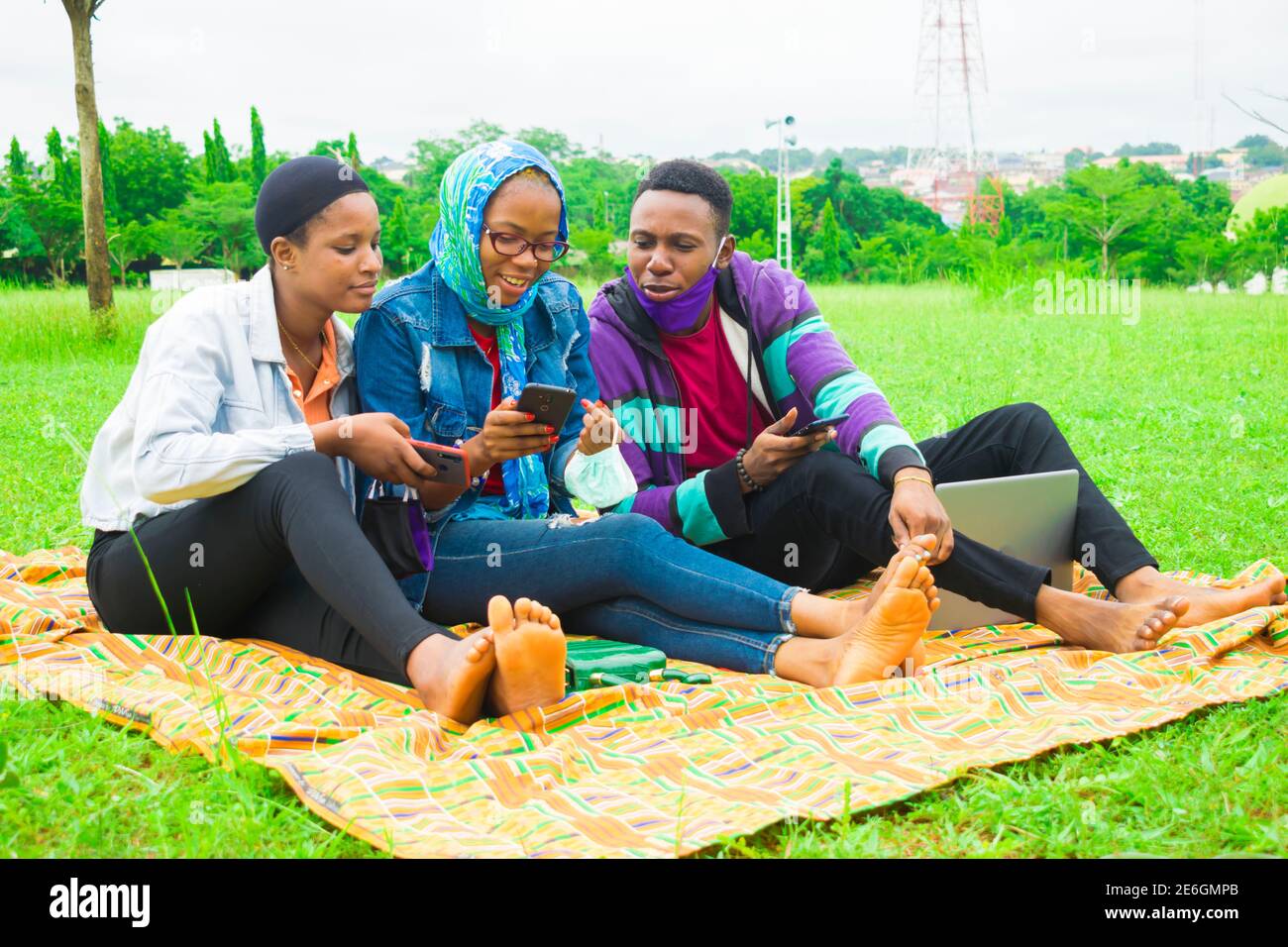 jeunes amis noirs assis et regardant un smartphone une belle femme utilise dans un parc Banque D'Images