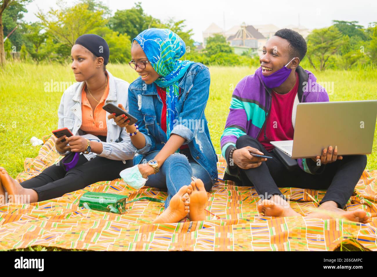 jeunes amis noirs assis et regardant un smartphone une belle femme utilise dans un parc Banque D'Images