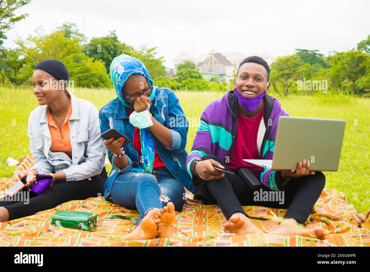 jeunes amis noirs assis et regardant un smartphone une belle femme utilise dans un parc Banque D'Images