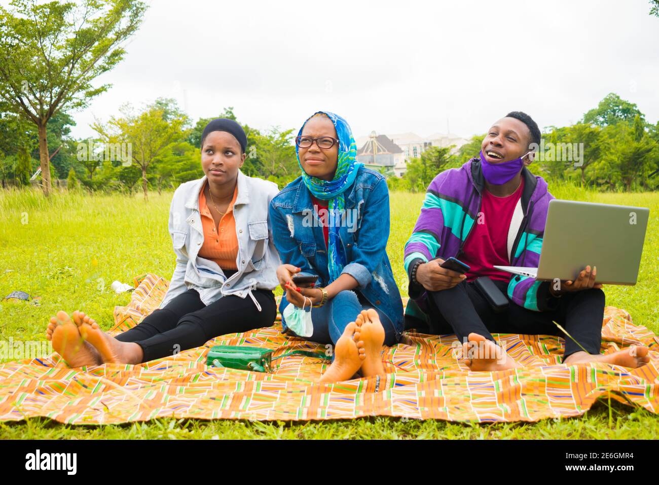 jeunes amis noirs assis et regardant un smartphone une belle femme utilise dans un parc Banque D'Images