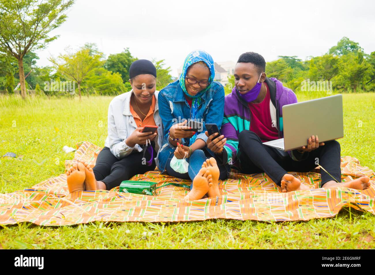 jeunes amis noirs assis et regardant un smartphone une belle femme utilise dans un parc Banque D'Images