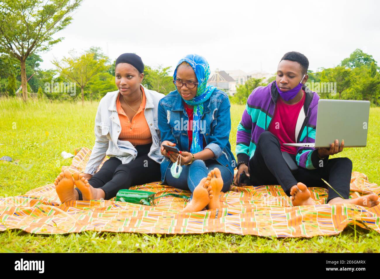 jeunes amis noirs assis et regardant un smartphone une belle femme utilise dans un parc Banque D'Images