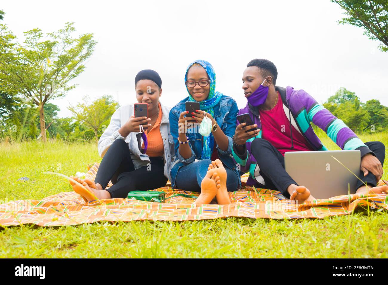 jeunes amis noirs assis et regardant un smartphone une belle femme utilise dans un parc Banque D'Images