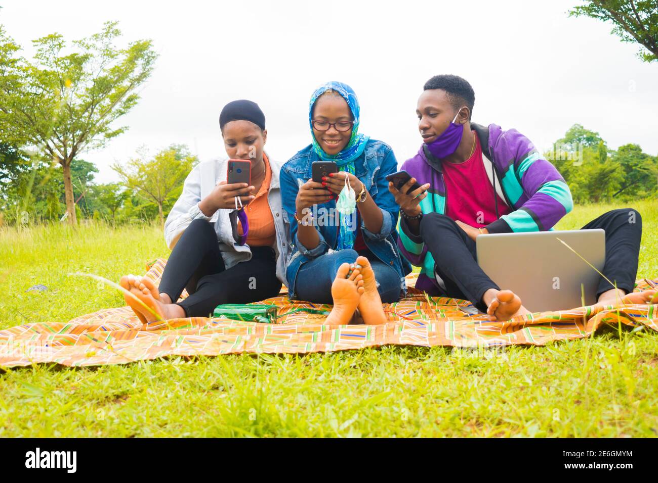 jeunes amis noirs assis et regardant un smartphone une belle femme utilise dans un parc Banque D'Images
