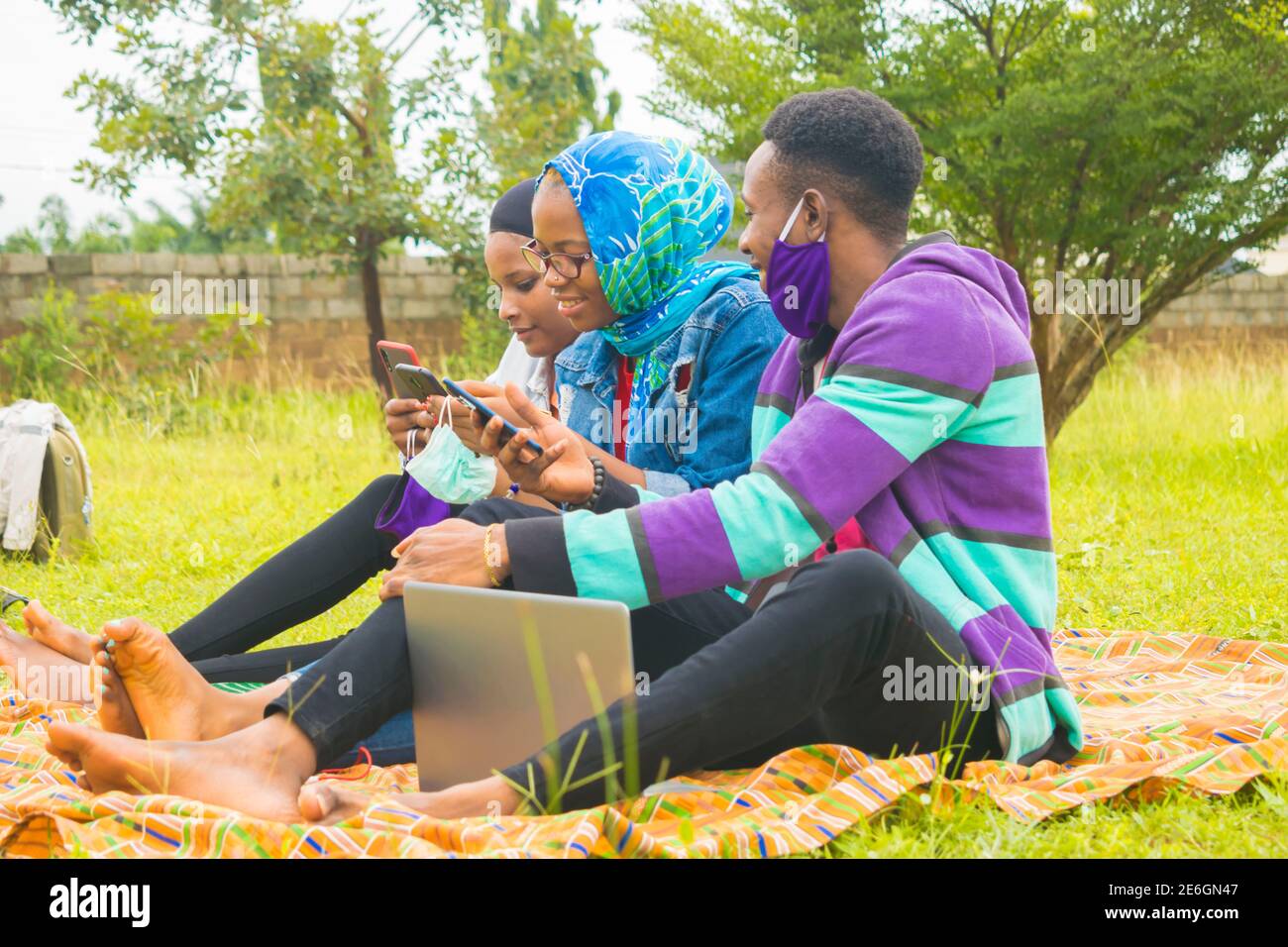 jeunes amis noirs assis et regardant un smartphone une belle femme utilise dans un parc Banque D'Images