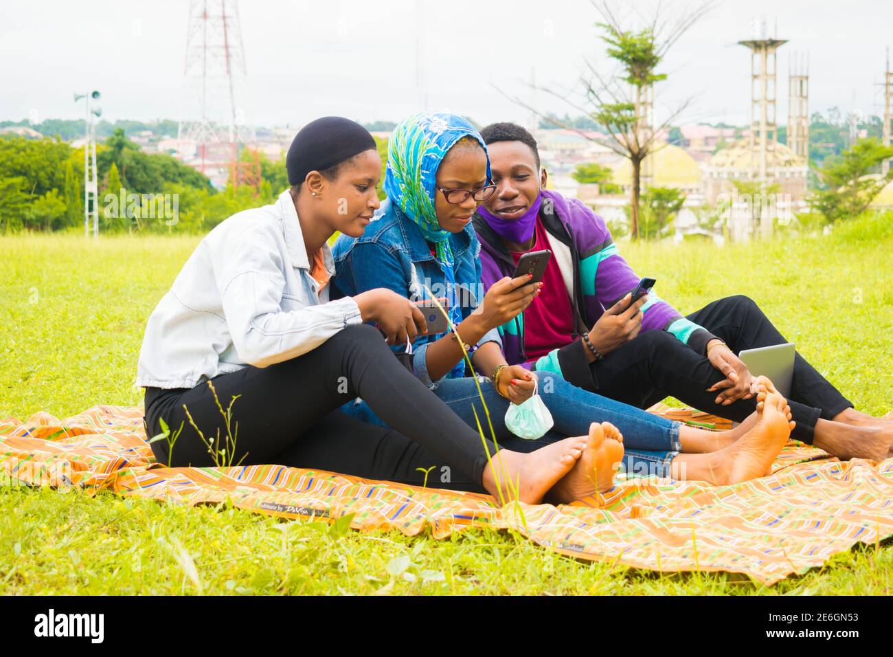 jeunes amis noirs assis et regardant un smartphone une belle femme utilise dans un parc Banque D'Images
