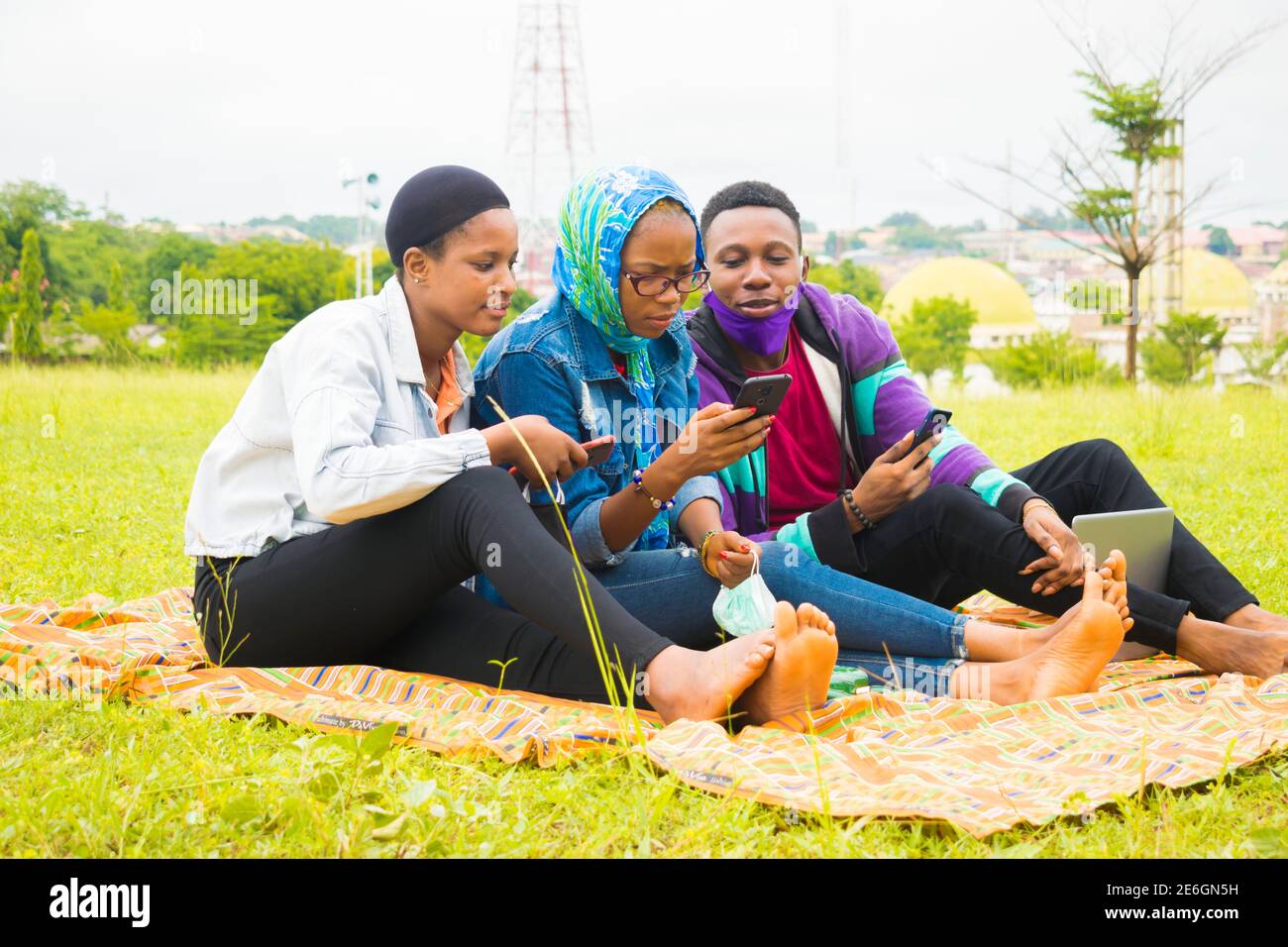 jeunes amis noirs assis et regardant un smartphone une belle femme utilise dans un parc Banque D'Images