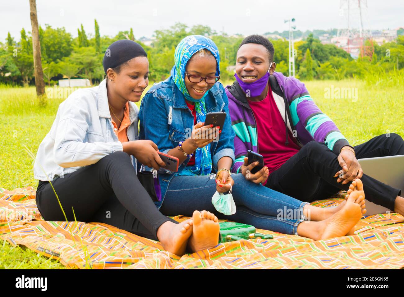 jeunes amis noirs assis et regardant un smartphone une belle femme utilise dans un parc Banque D'Images