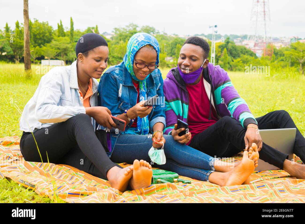 jeunes amis noirs assis et regardant un smartphone une belle femme utilise dans un parc Banque D'Images