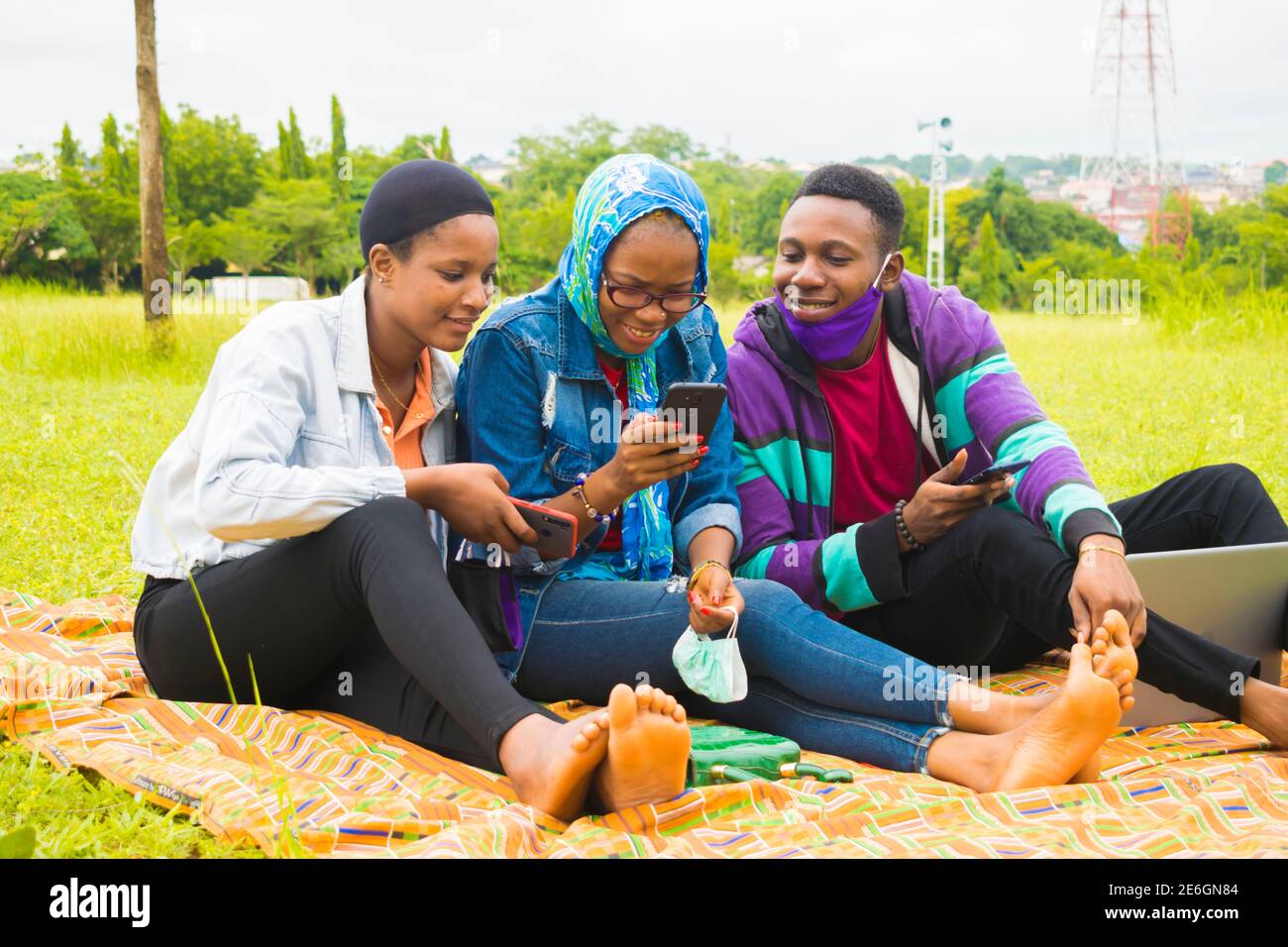 jeunes amis noirs assis et regardant un smartphone une belle femme utilise dans un parc Banque D'Images