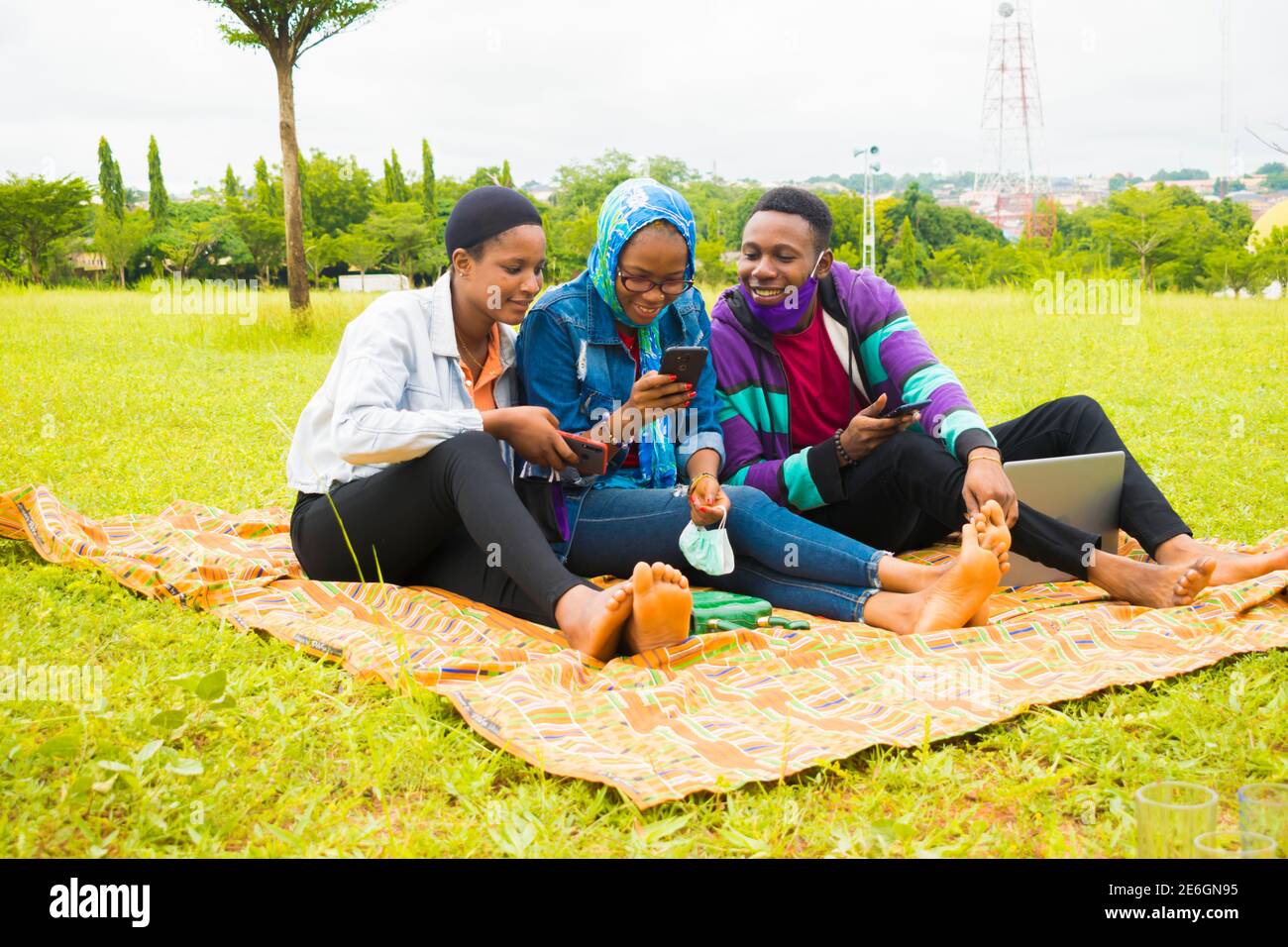 jeunes amis noirs assis et regardant un smartphone une belle femme utilise dans un parc Banque D'Images