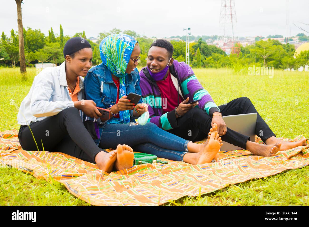 jeunes amis noirs assis et regardant un smartphone une belle femme utilise dans un parc Banque D'Images