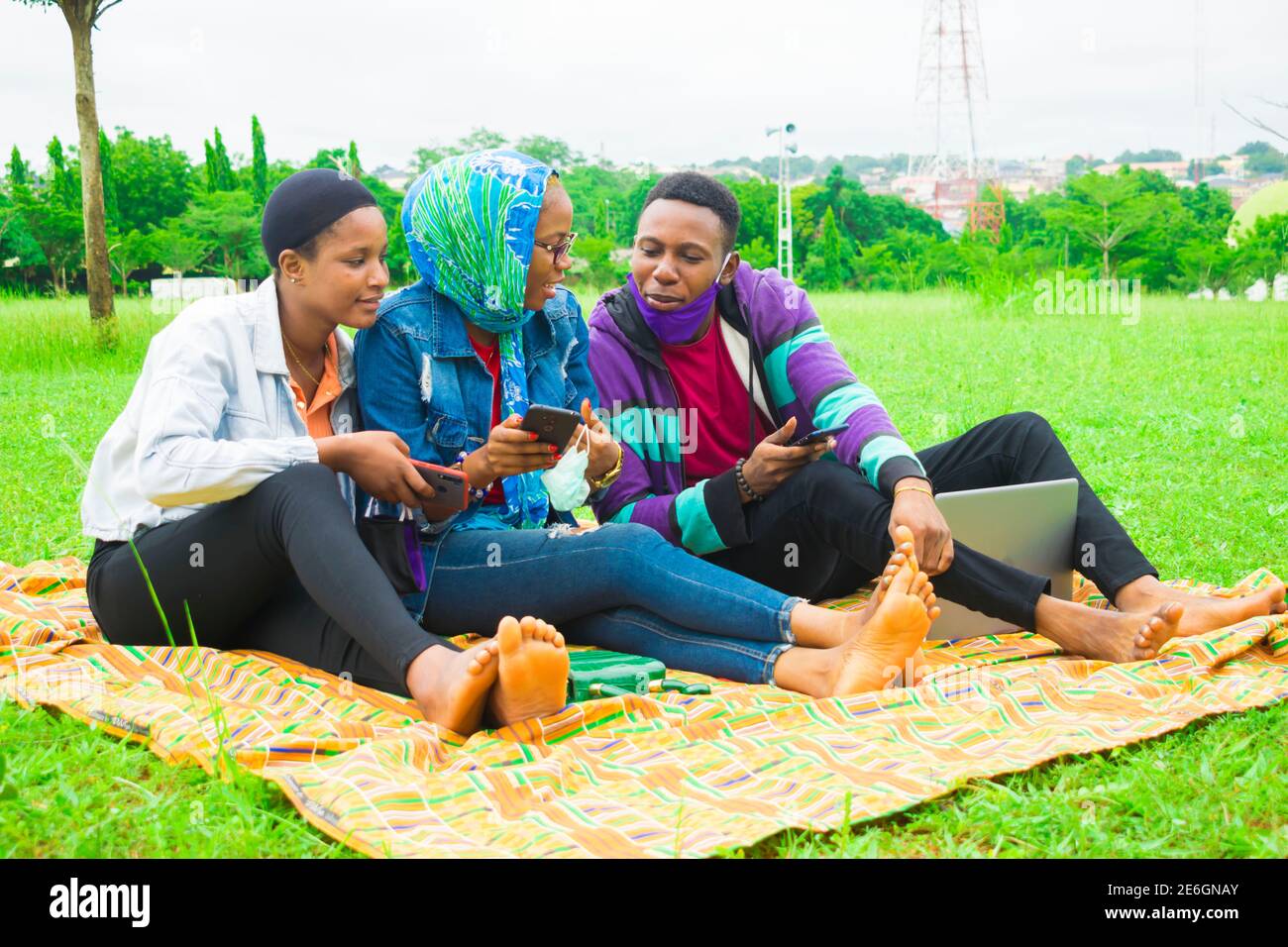 jeunes amis noirs assis et regardant un smartphone une belle femme utilise dans un parc Banque D'Images