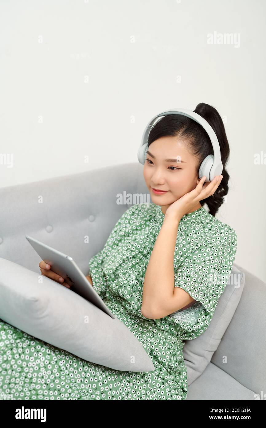smile femme écouter de la musique sur tablette numérique sur le canapé, beauté asiatique Banque D'Images