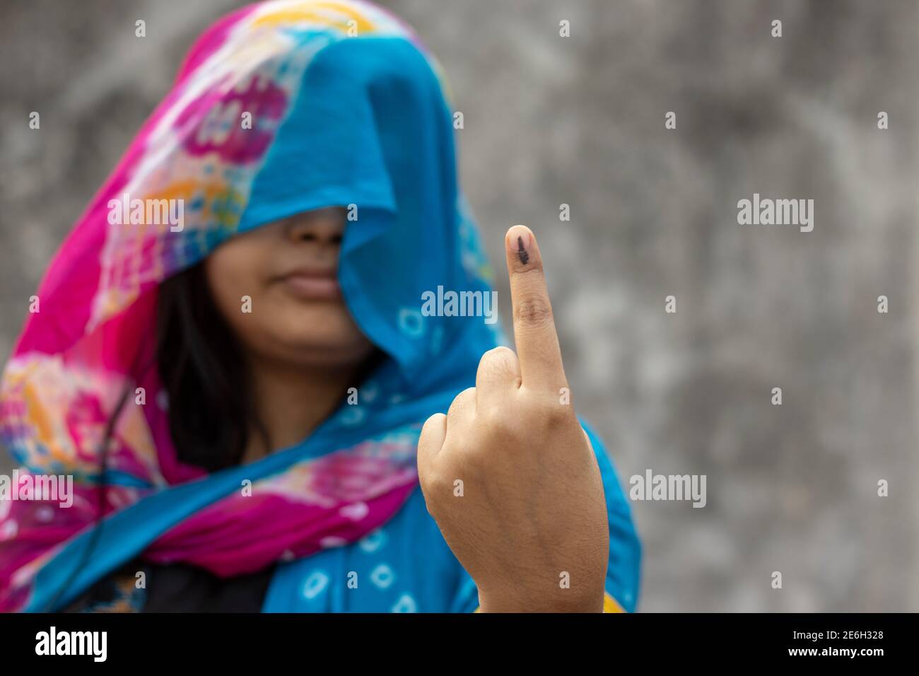 Accent sélectif sur le doigt marqué à l'encre d'une femme d'un village indien derrière un voile avec un visage souriant Banque D'Images