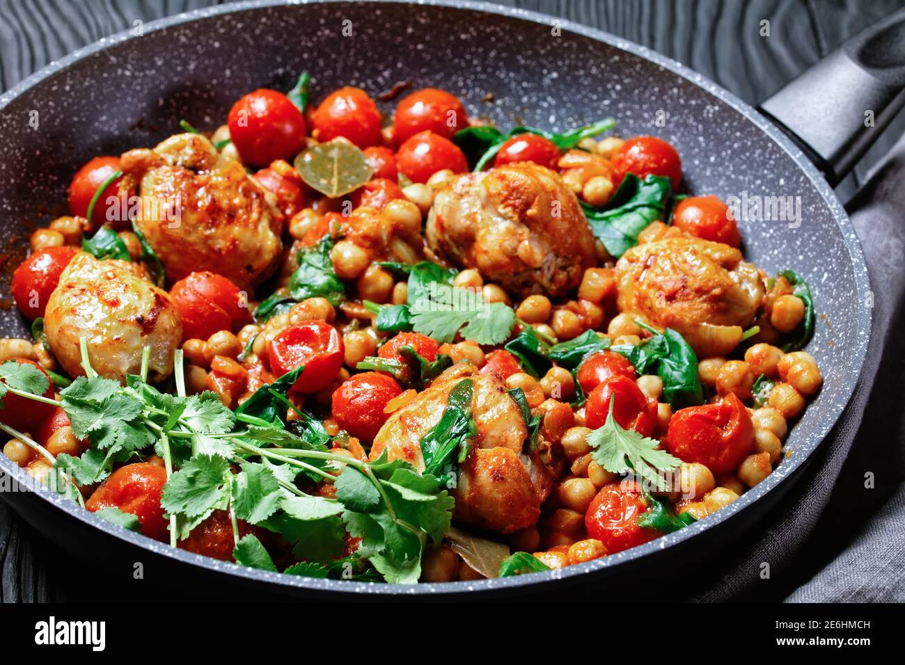 Curry traditionnel de poulet et de pois chiches de cuisses de poulet désossées avec tomates cerises, épinards, gingembre, servi avec de la coriandre fraîche sur une poêle o Banque D'Images