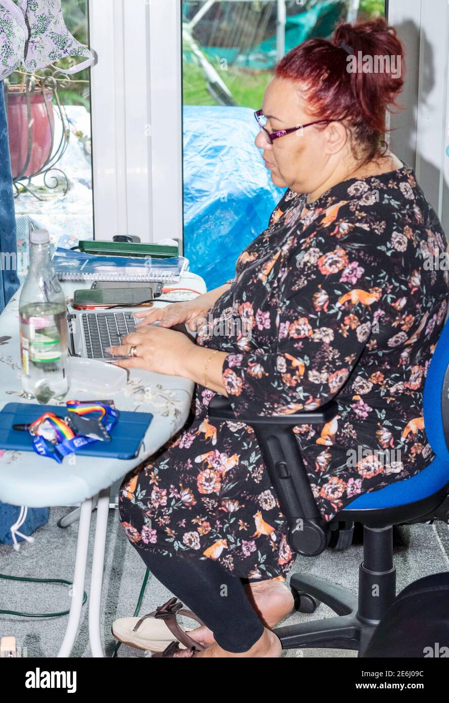 Femme noire travaillant à la maison (WFH) utilisant une planche à repasser pour un bureau dans un cadre domestique. Banque D'Images