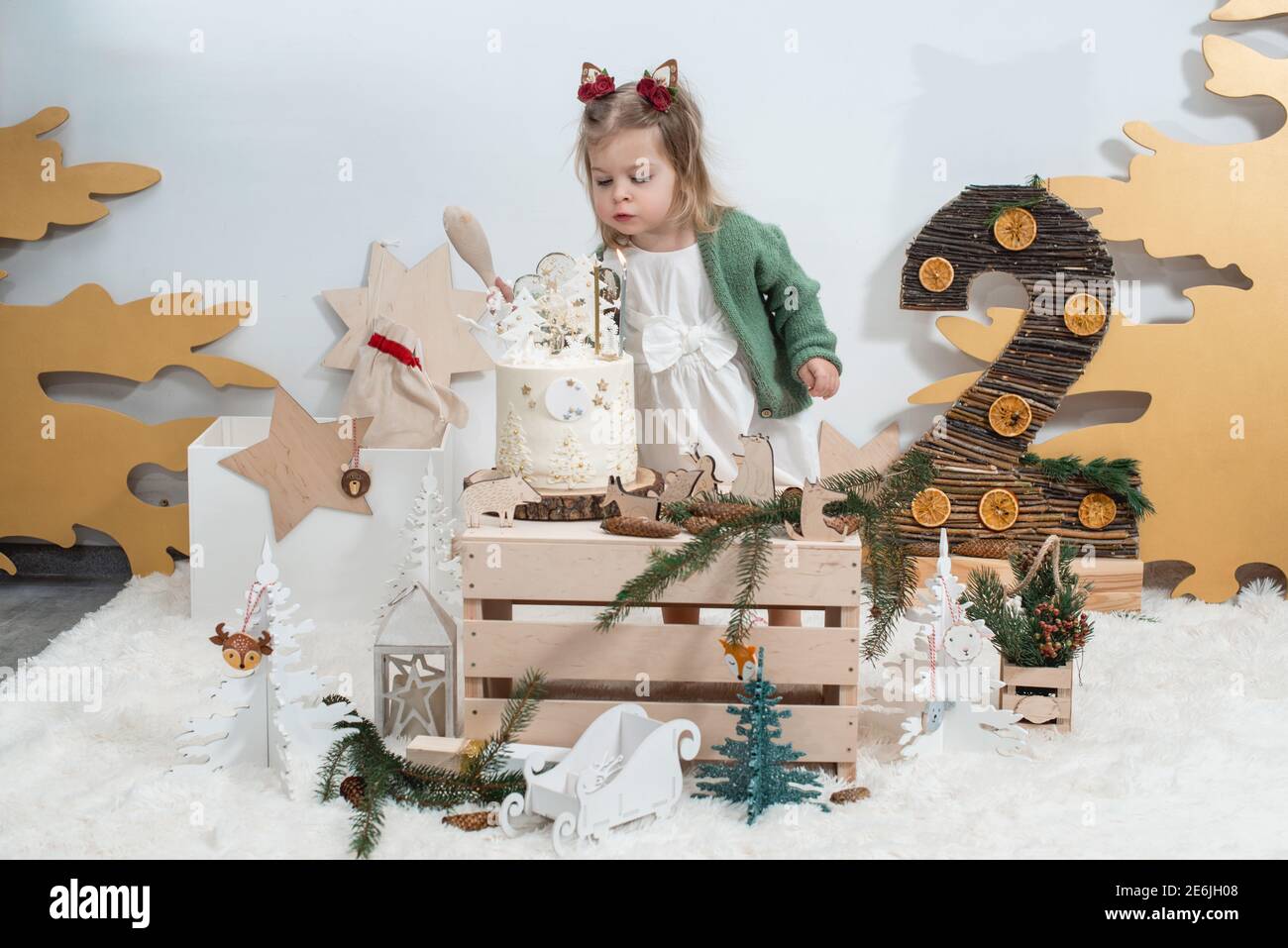 Decorations D Anniversaire D Hiver Pour Enfants 2 Ans Jolie Petite Fille Dans Un Gilet Vert Pres D Un Gateau D Anniversaire Blanc Photo Stock Alamy