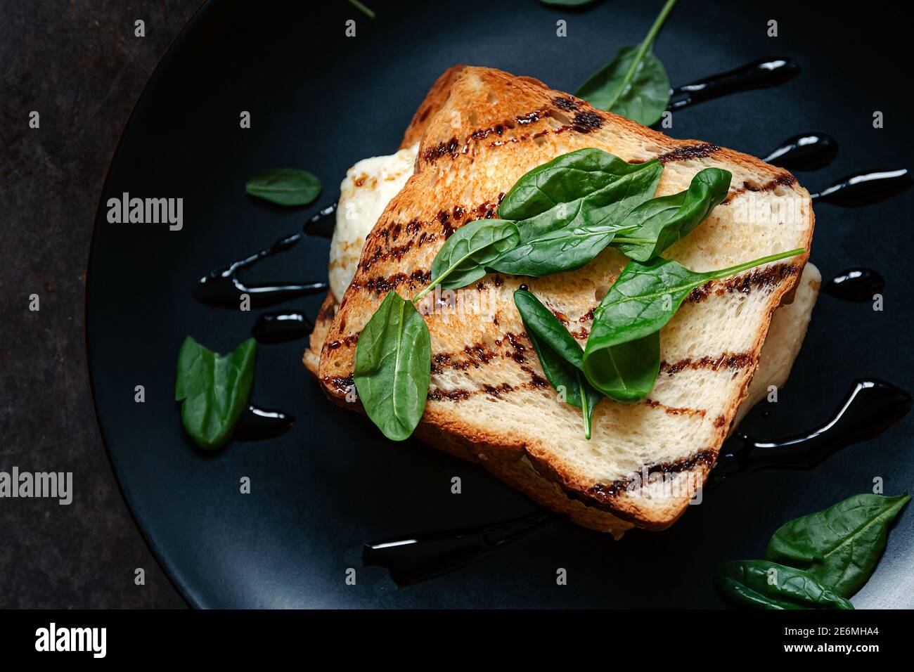 Sandwich sain au grain entier, pain grillé avec feuilles d'épinards verts frais, avocat, œuf de friture et sauce salée. Nourriture dans le fond. Idée, recette pour rapide Banque D'Images