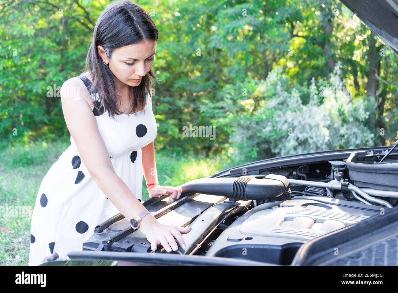 une jeune femme répare une voiture cassée. réparer une voiture. belle dame et voiture Banque D'Images