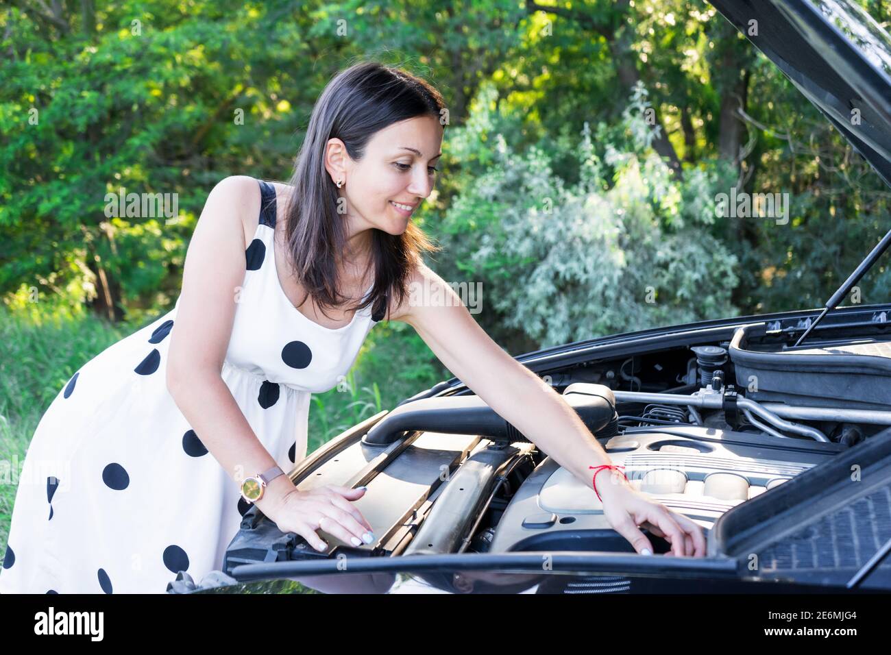 une jeune femme répare une voiture cassée. réparer une voiture. belle dame et voiture Banque D'Images