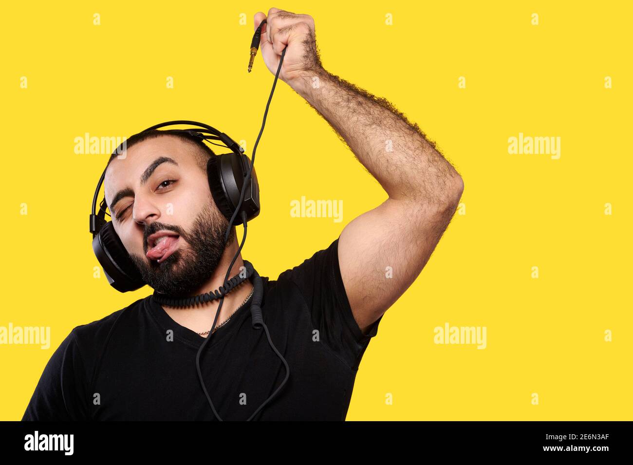 Drôle de musicien de dj drôle avec des écouteurs écoute la musique de chant par fil autour du cou sur fond jaune isolé Banque D'Images