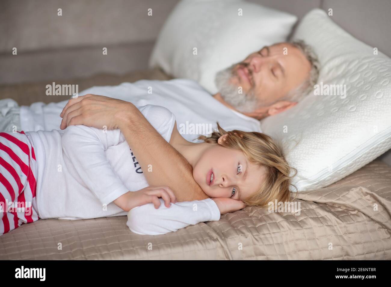 Un enfant endormi et un papa endormi l'embrassant Banque D'Images