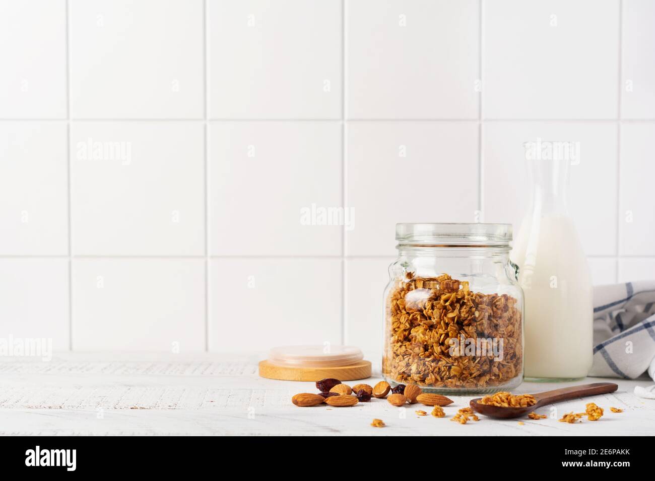 Granola d'avoine avec une bouteille de lait, de noix et de fruits secs, bols en céramique pour préparer un petit déjeuner sain sur une table lumineuse de cuisine. Merde scandinave Banque D'Images