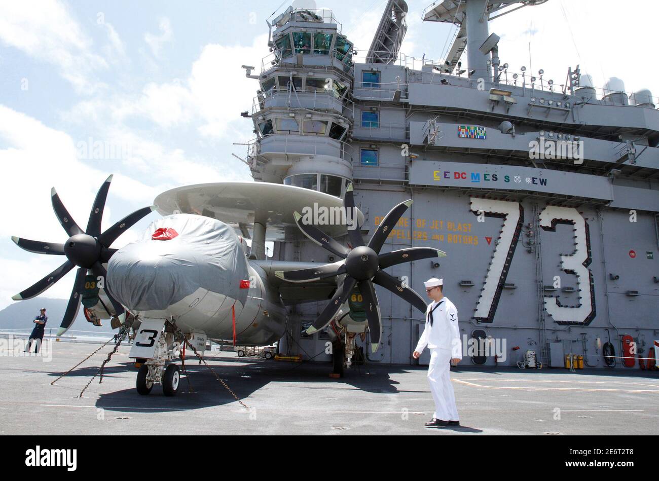 A U.S. Navy sailor of the nuclear-powered aircraft carrier USS George  Washington walks past a E-2C Hawkeye aircraft on a flight deck after the  aircraft arrived at a South Korean naval base