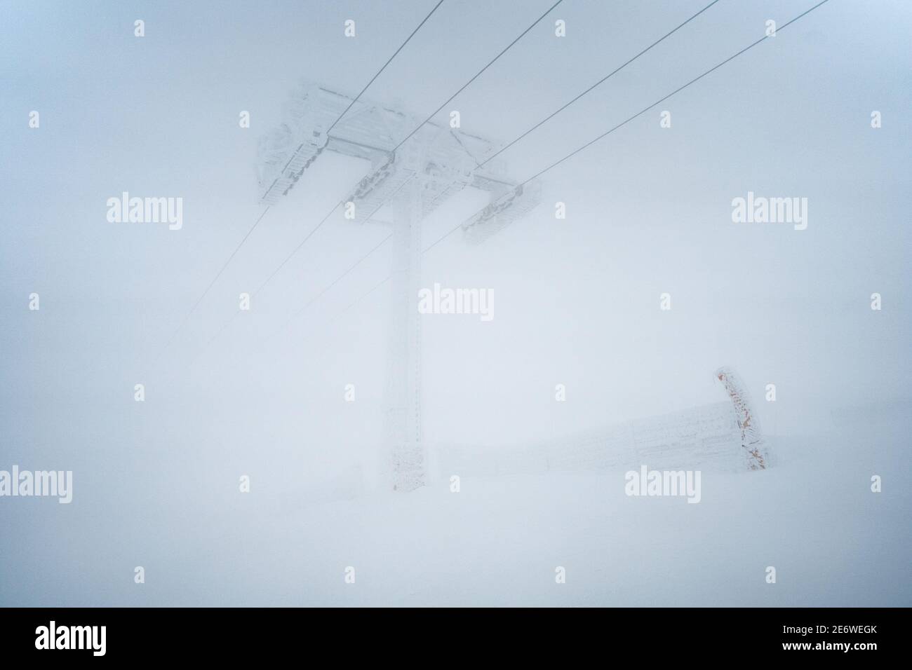 Les gens qui font du ski alpin pendant la tempête de neige. Les pistes de ski ont fermé le domaine skiable en raison du mauvais temps et du givrage. Homme athlète sur une pente enneigée par temps froid blanc Banque D'Images